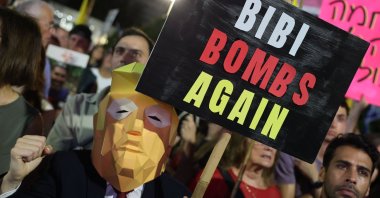 A protester wearing a mask representing Donald Trump carries a sign during a demonstration organized by the families of Israelis held hostage in Gaza Strip, Tel Aviv, Israel, Sept. 13, 2025. (AFP Photo)