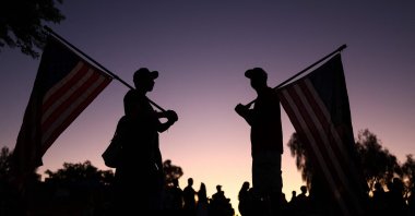 People hold American flags as they gather at a makeshift memorial for right-wing activist Charlie Kirk, Phoenix, Arizona, U.S., Sept. 14, 2025. (AFP Photo)