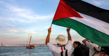 A man waves a Palestinian flag to other activists and human rights defenders riding aboard a vessel departing from the port of Bizerte, northern Tunisia, Sept. 14, 2025. (AFP Photo)