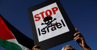 A demonstrator displays a placard next to a Palestinian flag during a protest calling for a trade and arms exports embargo against Israel, at the Puerta del Sol square in Madrid, Spain, Sept. 9, 2025. (Reuters Photo)