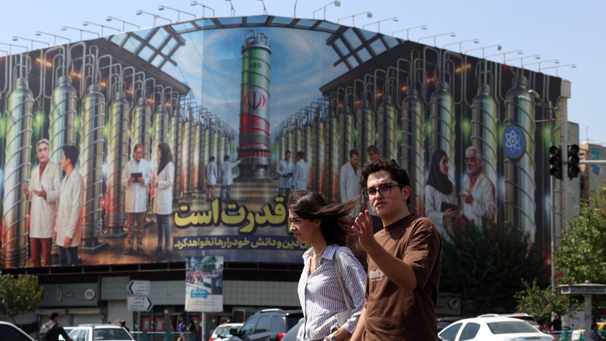Iranians cross a road near a billboard displaying a picture of nuclear centrifuges and a sentence reading in Persian &#039;Science is the power&#039; in Tehran, Iran, Aug. 29, 2025. (EPA Photo)