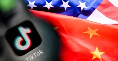 This photo shows the Chinese social networking service TikTok&#039;s logo on a smartphone screen (L) and U.S. and China flags combo illustration on a laptop screen in Frankfurt am Main, western Germany, April 10, 2025. (AFP Photo)