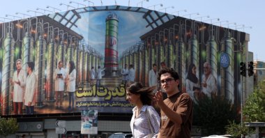 Iranians cross a road near a billboard displaying a picture of nuclear centrifuges and a sentence reading in Persian &#039;Science is the power&#039; in Tehran, Iran, Aug. 29, 2025. (EPA Photo)