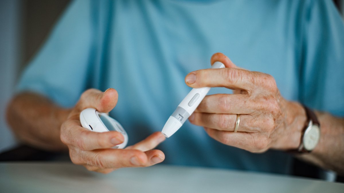 A man checks his blood sugar level with a fingerstick testing glucose meter. (Shutterstock Photo)