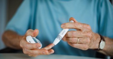A man checks his blood sugar level with a fingerstick testing glucose meter. (Shutterstock Photo)