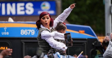 Rapper Cardi B holds a baby that was passed to her on the roof of her vehicle, as she hosts a pop-up event at a bodega, New York City, U.S., Sept. 13, 2025. (Reuters Photo)