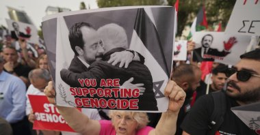 A protester holds a poster showing Greek Cypriot leader Nikos Christodoulides and Israeli Prime Minister Benjamin Netanyahu embracing, Lefkoşa (Nicosia), TRNC, May 26, 2025. (AP Photo)