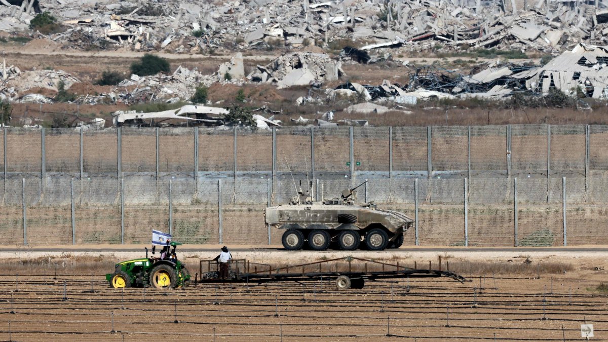  A farmer works on a field as an Israeli army vehicle moves along the separation fence on the border with the Gaza Strip in southern Israel, Sept. 19, 2025. (AFP Photo)