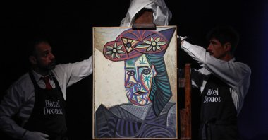 Employees unveal a painting by Spanish artist Pablo Picasso titled &quot;Bust of a woman with a flowery hat&quot; and featuring one his lovers Dora Maar, during its presentation at Hotel Drouot auction house, Paris, France, Sept. 18, 2025. (AFP Photo)