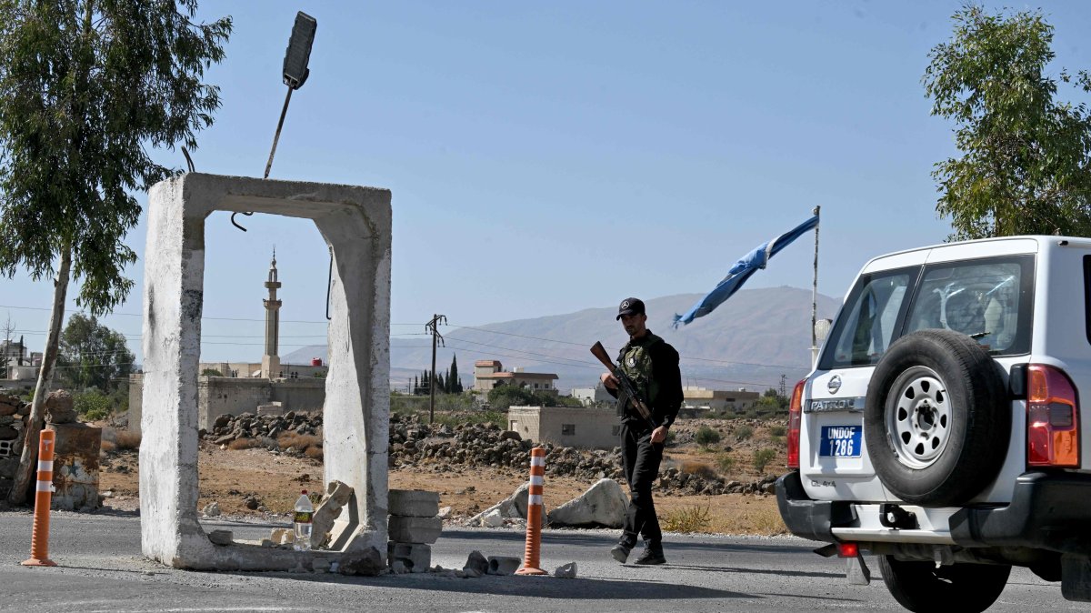 A U.N. Disengagement Observatory Force (UNDOF) vehicle drives past a member of Syria&#039;s security forces standing guard outside a former army base, near Quneitra, southern Syria, Sept. 21, 2025. (AFP Photo)