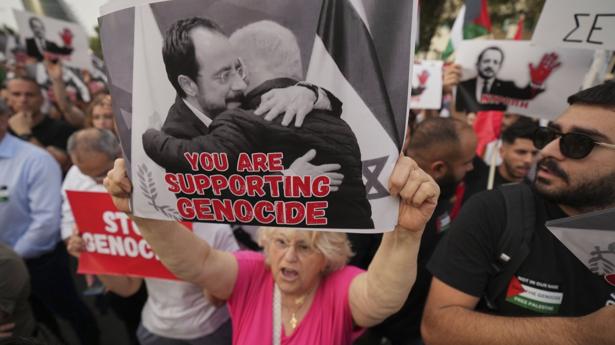 A protester holds a poster showing Greek Cypriot leader Nikos Christodoulides and Israeli Prime Minister Benjamin Netanyahu embracing, Lefkoşa (Nicosia), TRNC, May 26, 2025. (AP Photo)