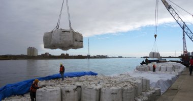 Workers stand near a crane unloading sacks of imported soybeans from Russia, Heihe port, Heilongjiang province, China, Oct. 10, 2018. (Reuters Photo)