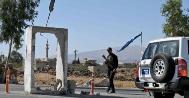 A U.N. Disengagement Observatory Force (UNDOF) vehicle drives past a member of Syria&#039;s security forces standing guard outside a former army base, near Quneitra, southern Syria, Sept. 21, 2025. (AFP Photo)