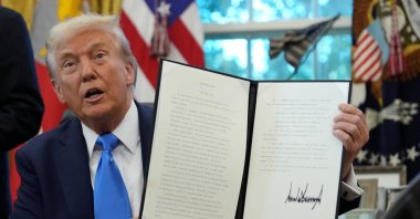 U.S. President Donald Trump displays a signed executive order on a gold card visa in the Oval Office at the White House in Washington, D.C., U.S., Sept. 19, 2025. (Reuters Photo)