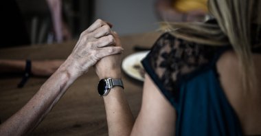 A volunteer (R) holding the hand of an Alzheimer’s patient during lunch at the restaurant of the village Landais Alzheimer site for Alzheimer’s patients, Dax, France, Sept. 9, 2020. (AFP Photo)