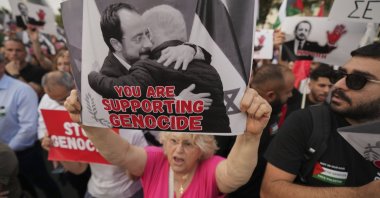 A protester holds a poster showing Greek Cypriot leader Nikos Christodoulides and Israeli Prime Minister Benjamin Netanyahu embracing, Lefkoşa (Nicosia), TRNC, May 26, 2025. (AP Photo)