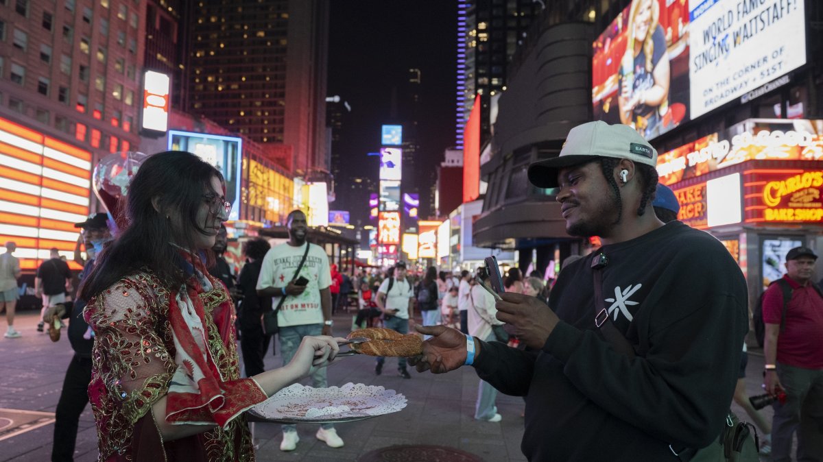 A woman hands over traditional Turkish simit to a visitor in Times Square, New York, U.S., Sept. 23, 2025. (AA Photo)