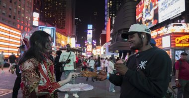 A woman hands over traditional Turkish simit to a visitor in Times Square, New York, U.S., Sept. 23, 2025. (AA Photo)