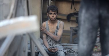 A Palestinian youth sits amid the rubble from a building destroyed in an Israeli attack, central Gaza, Palestine, Sept. 25, 2025. (AA Photo)