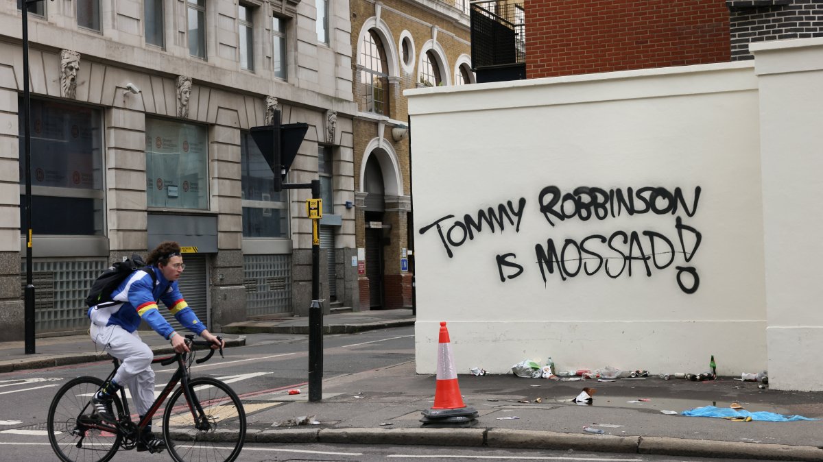 A cyclist rides past a wall painted with graffiti the day after an anti-immigration rally organized by British anti-immigration activist Stephen Yaxley-Lennon, also known as Tommy Robinson, London, Britain, Sept. 14, 2025. (Reuters Photo)