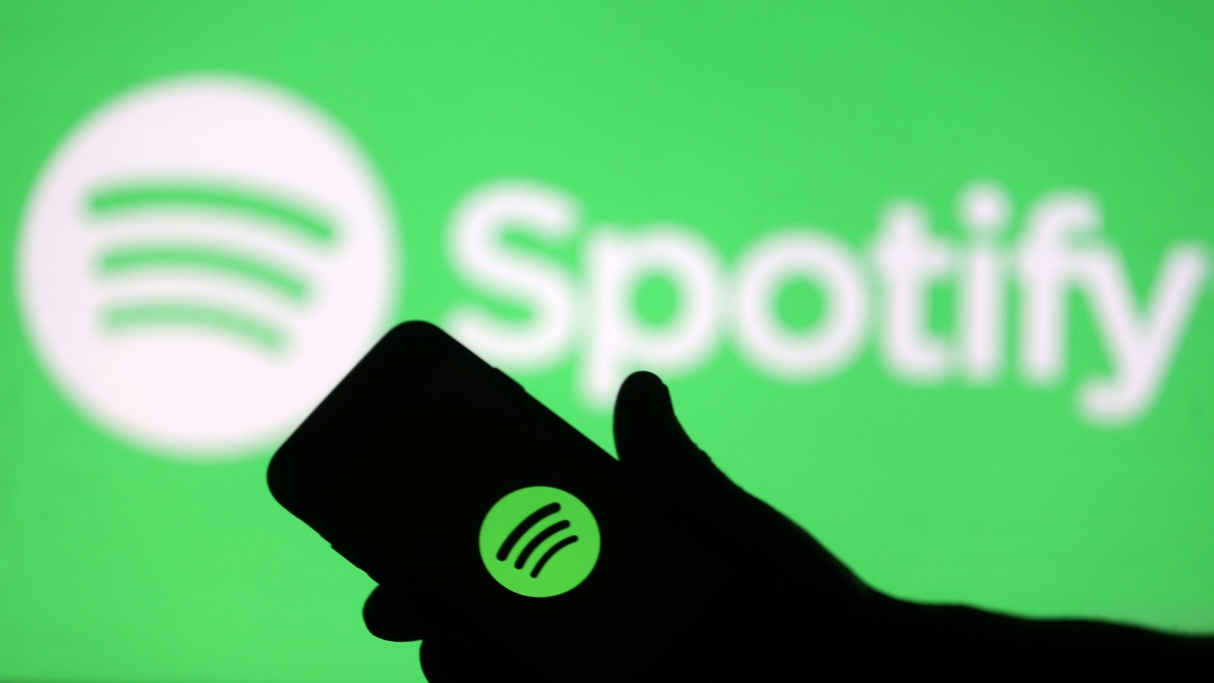 A smartphone is seen in front of a screen projection of the Spotify logo, in this picture illustration taken April 1, 2018. (Reuters File Photo)