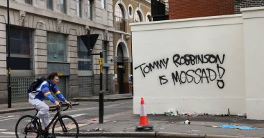 A cyclist rides past a wall painted with graffiti the day after an anti-immigration rally organized by British anti-immigration activist Stephen Yaxley-Lennon, also known as Tommy Robinson, London, Britain, Sept. 14, 2025. (Reuters Photo)