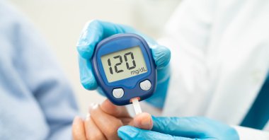 A doctor uses a digital glucose monitor to check a patient&#039;s blood sugar level. (Shutterstock Photo)