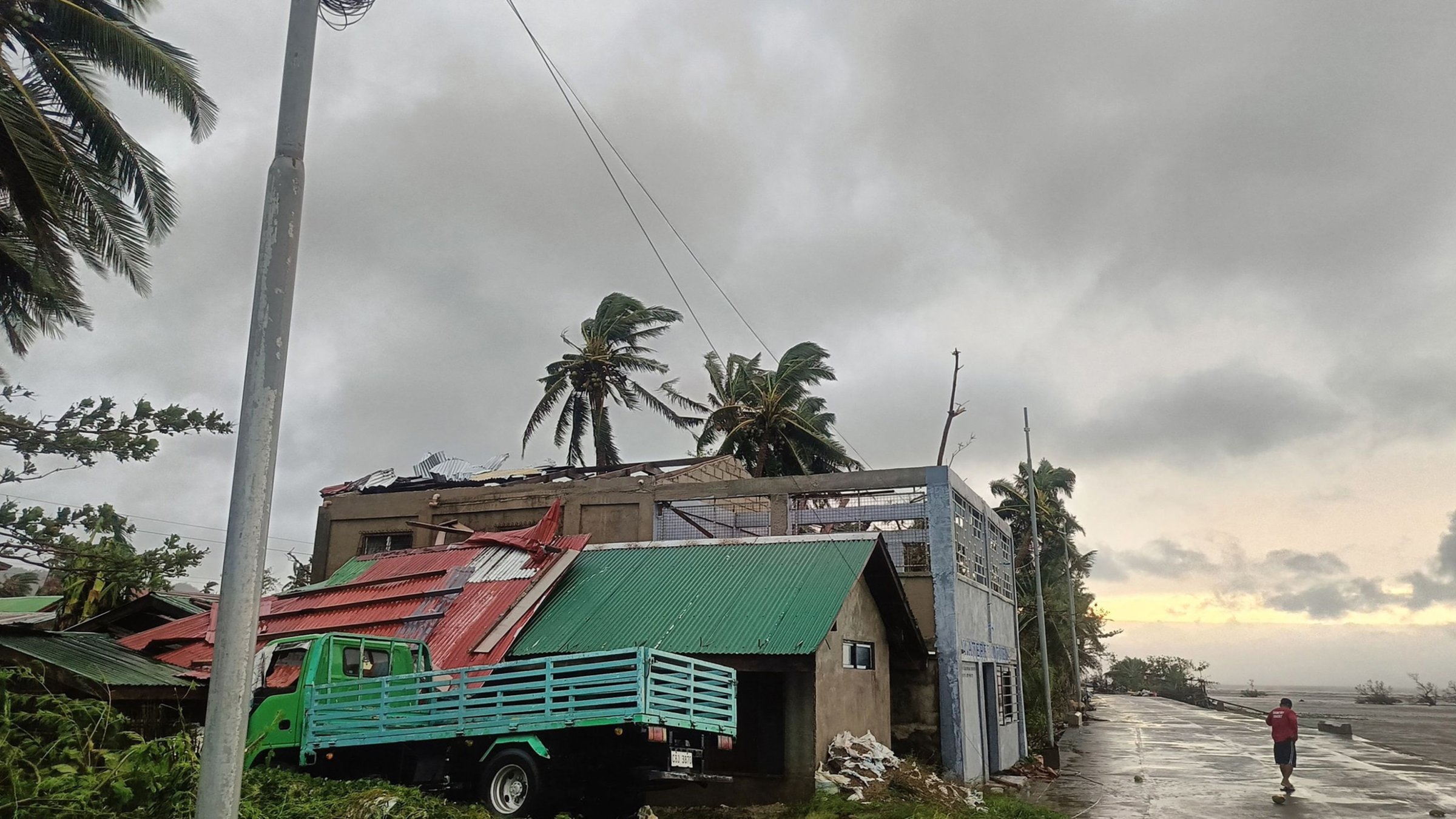 A resident walking past a building with a ripped roof destroyed at the height of Severe Tropical Storm (STS) Bualoi, Masbate City, Bicol region, Manila, Philippines, Sept. 26, 2025. (AFP Photo)
