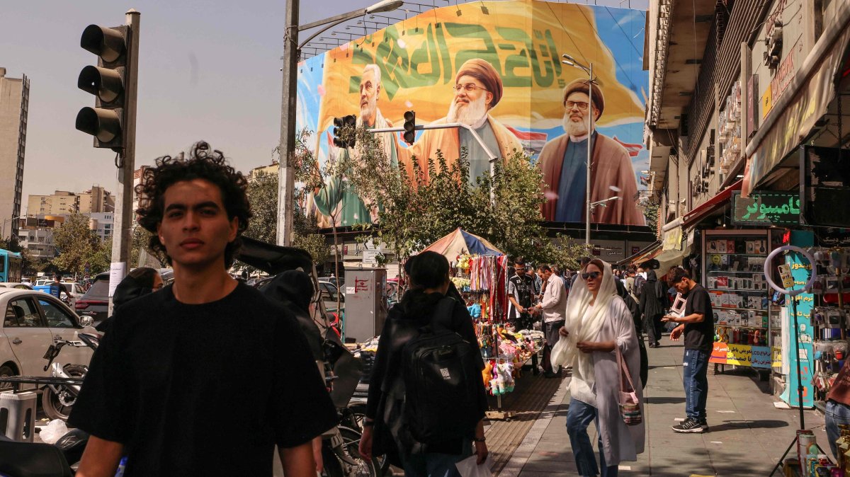 People walk in front of a billboard depicting slain Lebanese Hezbollah leaders Hassan Nasrallah (C) and his successor Hashem Safieddine (R) as well as the late Iranian General Qasem Soleimani, in Tehran, Iran, Sept. 28, 2025. (AFP Photo)