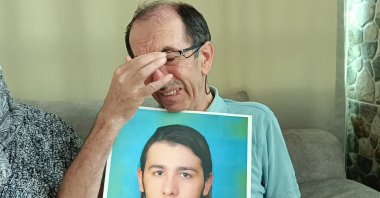 Hasan Dölek, father of Furkan Dölek, holds a photo of his son while awaiting news, Kozan, Adana, Türkiye, Sept. 2, 2025. (AA Photo)
