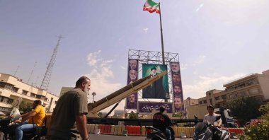 Iranians ride their motorcycles past a deactivated Kheibar Shekan ballistic missile in front of a picture of Iran&#039;s Supreme Leader Ayatollah Ali Khamenei in Tehran, Iran, Sept. 27, 2025. (AFP Photo)