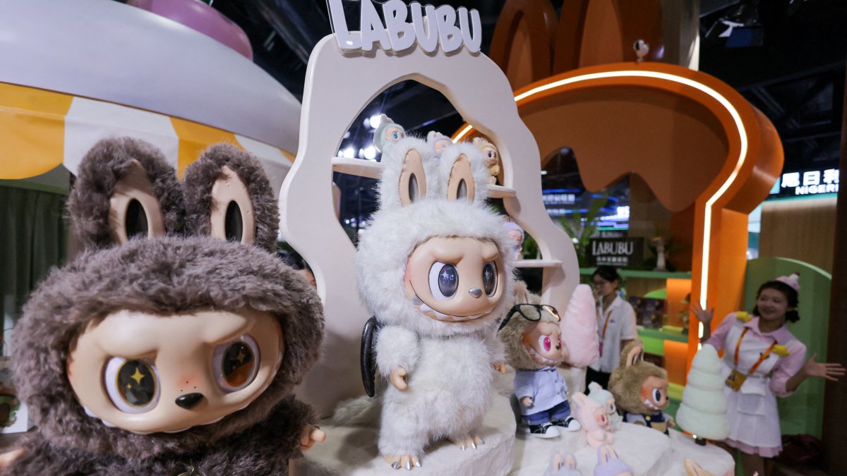 An employee gestures next to Labubu toys on display at Pop Mart’s booth at China International Fair for Trade in Services (CIFTIS) in Beijing, China, Sept. 10, 2025. (Reuters Photo)