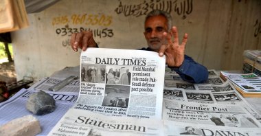 A man picks up a newspaper with the front page featuring news about Saudi Arabia signing a mutual defense pact with nuclear-armed Pakistan after Israel&#039;s attack on Qatar, Peshawar, Pakistan, Sept. 19, 2025. (EPA Photo)