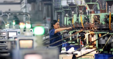 A woman works at an electronics factory in Chongqing, southwest China, Sept. 13, 2025. (AFP Photo)