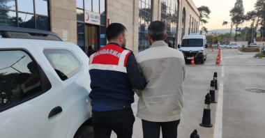 Gendarmerie officer escorts a FETÖ suspect, Izmir, Türkiye, Sept. 30, 2025. (AA Photo)