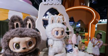 An employee gestures next to Labubu toys on display at Pop Mart’s booth at China International Fair for Trade in Services (CIFTIS) in Beijing, China, Sept. 10, 2025. (Reuters Photo)