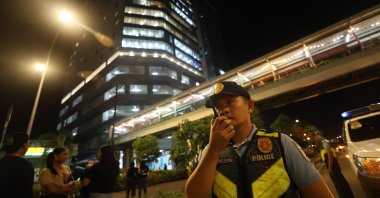 A Filipino police officer holds a radio outside an office building after an earthquake in Ilo-Ilo city, Philippines, Sept. 30, 2025. (EPA Photo)