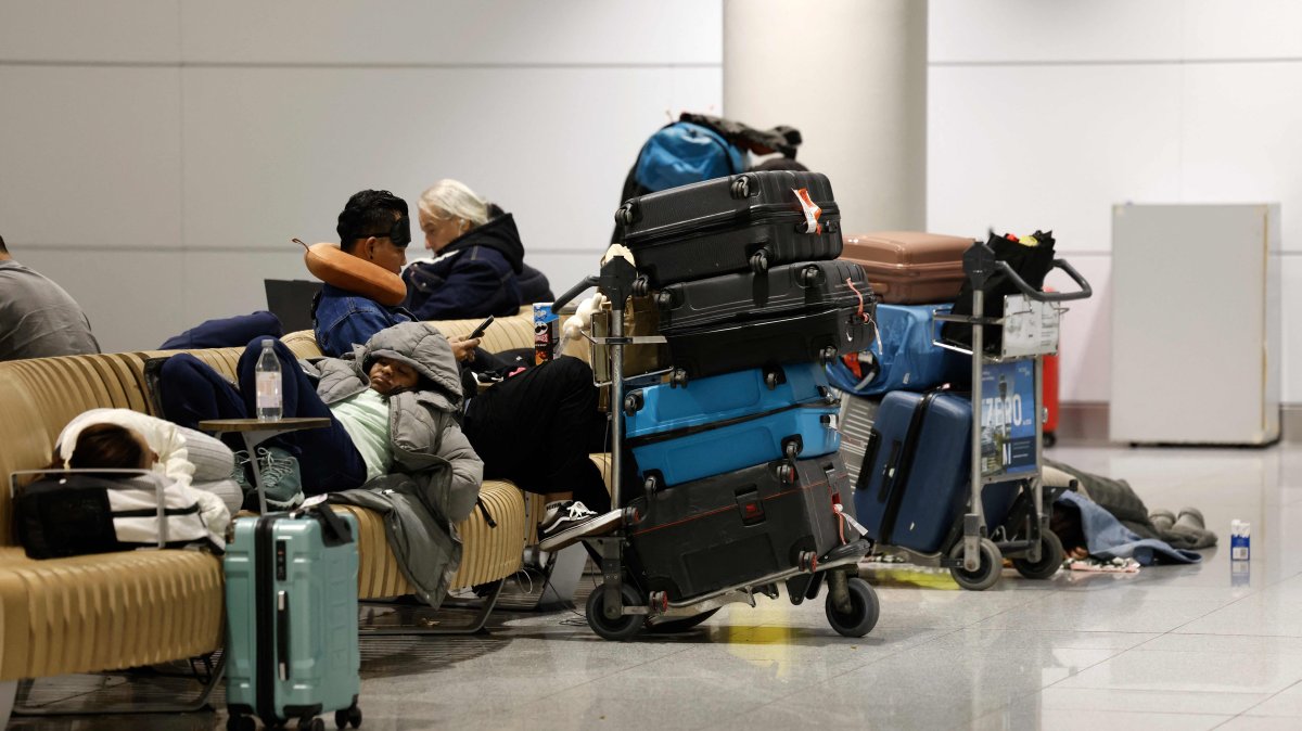 Passengers sit and lie on benches next to their luggage after reports of drone sightings canceled flights, at Munich International Airport in Munich, southern Germany, early Oct. 4, 2025. (AFP Photo)