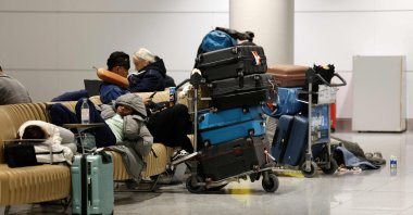 Passengers sit and lie on benches next to their luggage after reports of drone sightings canceled flights, at Munich International Airport in Munich, southern Germany, early Oct. 4, 2025. (AFP Photo)