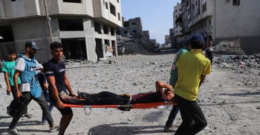 People carry an injured man on a stretcher, as Palestinians inspect the damage at a residential neighborhood, following an Israeli operation in the area, after Hamas agreed to release hostages and accept some other terms in a U.S. plan to end the war, in Gaza City, Oct. 4, 2025. (Reuters Photo)