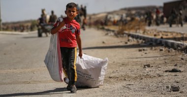 A Palestinian boy carries a bag and drags another behind him as he returns from a GHF food distribution point, near the Netsarim corridor in the central Gaza Strip, Palestine, Oct. 5, 2025. (AFP Photo)