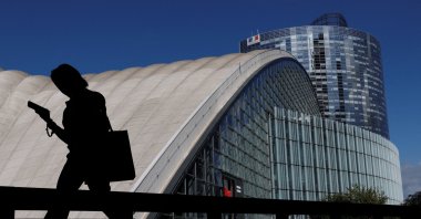 A person looking at the mobile phone walks past buildings at the financial and business district of La Defense in Puteaux near Paris, France, Sept. 12, 2025. (Reuters Photo)