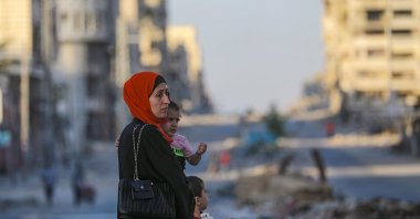 A Palestinian mother carrying her daughter moves at Al Jalaa street during an Israeli military operation in Gaza City, Gaza Strip, Oct. 6, 2025. (EPA Photo)