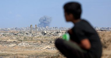 A Palestinian child sits in front of the scene of rising smoke following explosions amid the Israeli offensive, Gaza City, central Gaza Strip, Palestine, Oct. 6, 2025. (Reuters Photo)