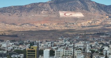A flag of the Turkish Republic of Northern Cyprus (TRNC) and the motto of Mustafa Kemal Atatürk, &quot;Ne mutlu Türküm diyene&quot; (&quot;Happy is he who calls himself a Turk&quot;), are seen on the slopes of the Beşparmak Mountains overlooking Lefkoşa (Nicosia), TRNC, Oct. 5, 2024. (AA Photo)