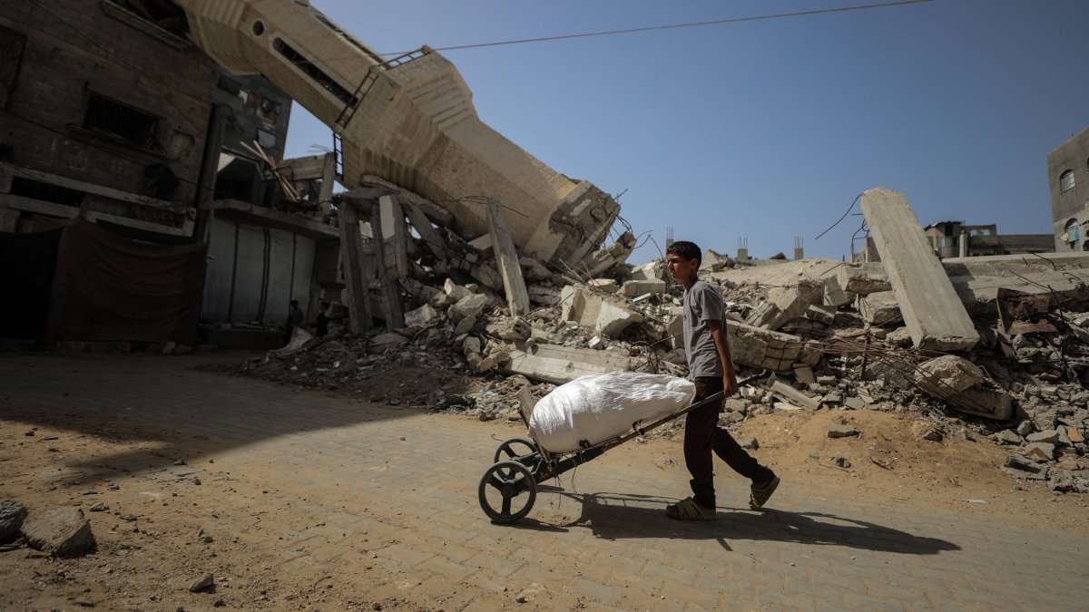 A Palestinian youth pushes a cart in front of a mosque destroyed in an Israeli attack, Nuseirat, central Gaza Strip, Palestine, Oct. 8, 2025. (AA Photo)  