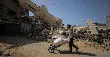 A Palestinian youth pushes a cart in front of a mosque destroyed in an Israeli attack, Nuseirat, central Gaza Strip, Palestine, Oct. 8, 2025. (AA Photo)  