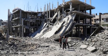 Palestinians walk past a destroyed building, Gaza City, Palestine, Oct. 8, 2025. (Reuters Photo)