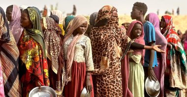 People who fled the Zamzam camp for the internally displaced after it fell under RSF control, queue for food rations in a makeshift encampment in an open field near the town of Tawila in war-torn western Darfur region, Sudan, April 13, 2025. (AFP Photo)