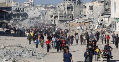 Palestinians walk past rubble following Israeli forces&#039; withdrawal from the area, amid a ceasefire between Israel and Hamas in Gaza, in Khan Younis, in the southern Gaza Strip, Oct. 11, 2025. (Reuters Photo)